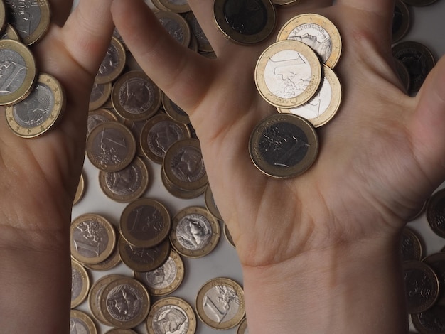 A person is holding up a stack of euro coins.