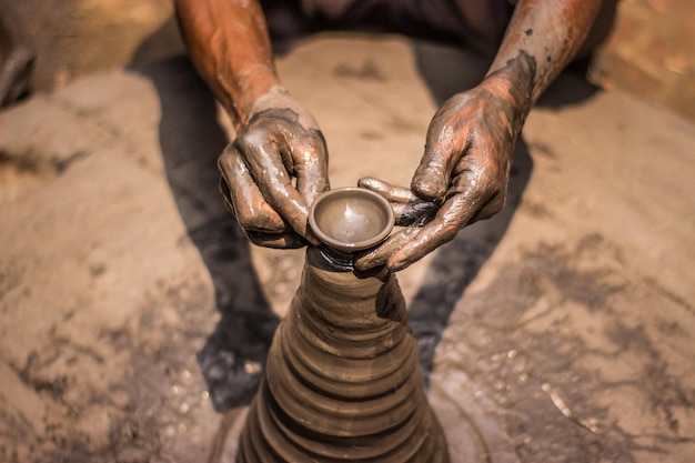 A person is making a clay pot with their hands.