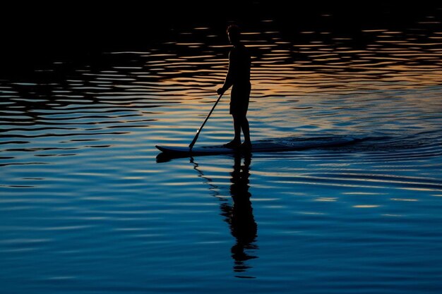 a person is on a paddle board with the sun setting behind them