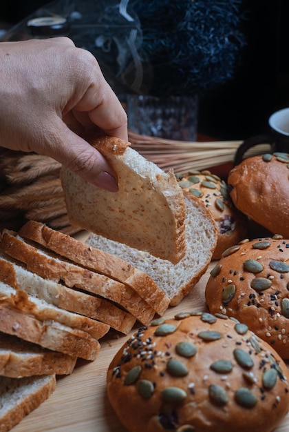 A person is picking up a piece of bread from a tray of bread.