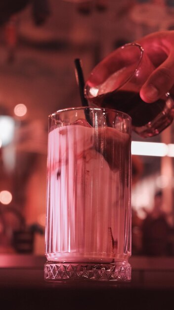 a person is pouring a drink in a glass with a straw