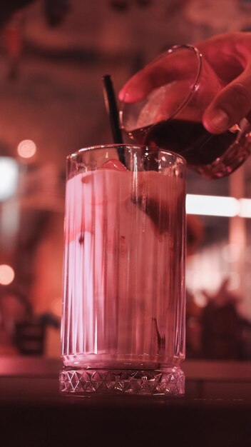 a person is pouring a drink in a glass with a straw