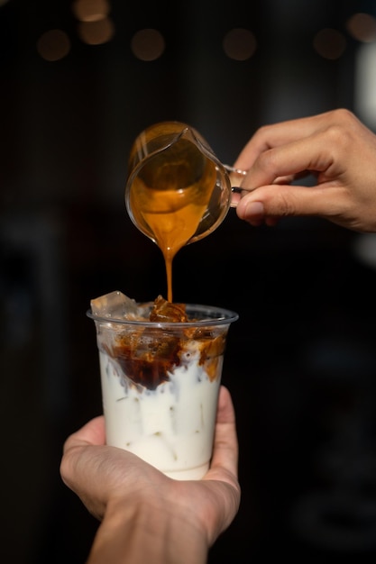 A person is pouring a glass of yogurt into a cup.