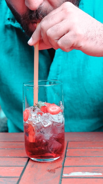 a person is pouring a straw into a glass of ice water