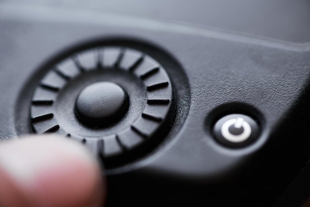 A person is pressing a button on a black remote.