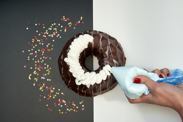 A person is putting a chocolate donut on a paper with a white background and a red and blue sign that says " donut ".