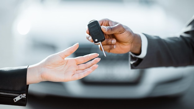 A person is receiving car keys from another person outdoors the person giving the keys is wearing a