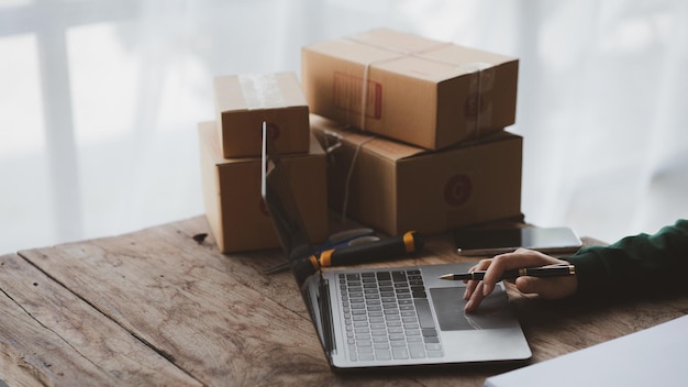 A person is using a laptop Business owner opens an online store she is checking orders from customers sending goods through a courier company concept of a opening an online business