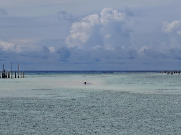 A person is in the water with a cloud in the sky