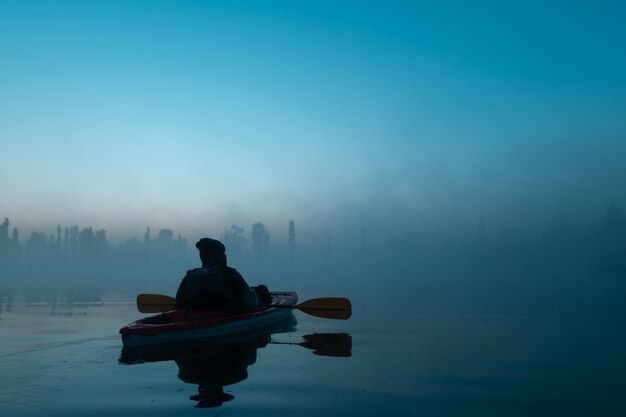 Photo person in a kayak in the xochimilco canal at dawn with fog