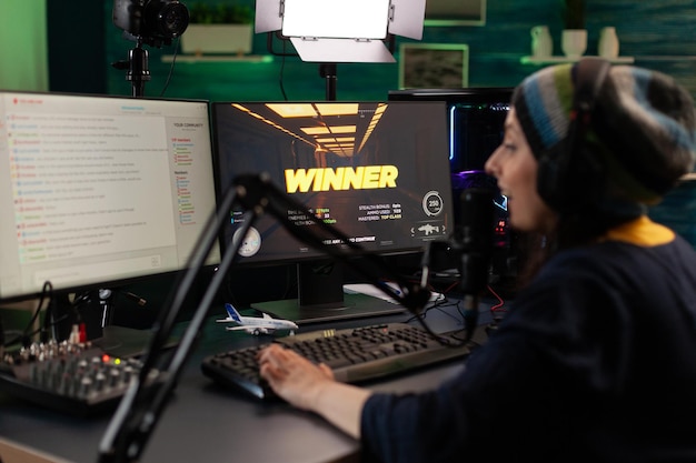 Person live streaming video games on monitor. woman\
broadcasting gameplay, playing online on stream with live chat,\
using monitor and microphone. streamer wearing headphones to\
play.