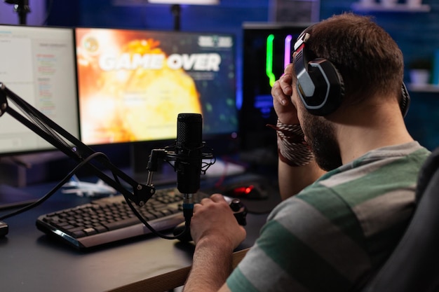 Person losing video games on live stream with chat. Man using headphones and microphone to broadcast gameplay, streaming lost game on computer. Gamer playing online on social media.