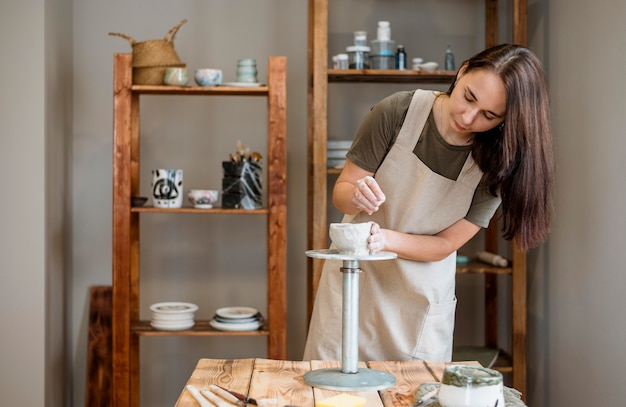 Person making a clay pot in her workshop