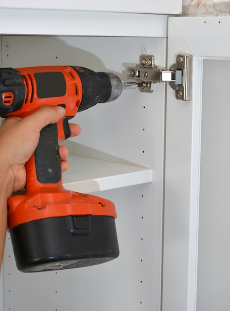 Person making a white wooden wardrobe with screws