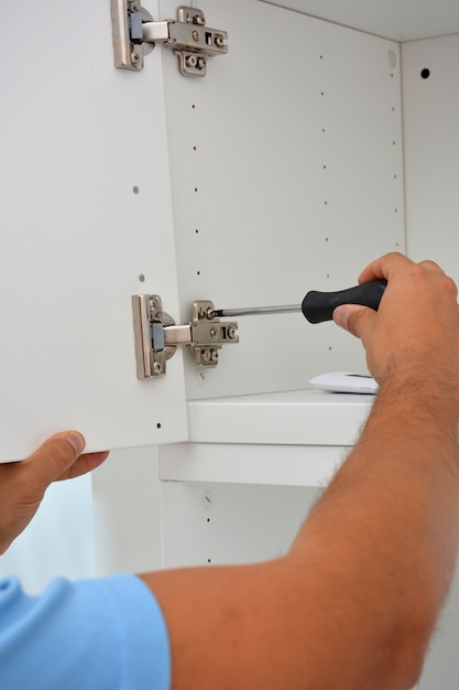 Person making a white wooden wardrobe with screws