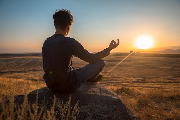 A person meditating in the field at the sunsetxA