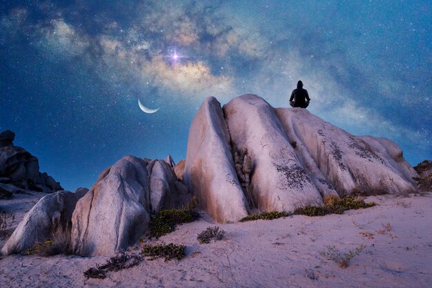 Person meditating outdoors at night under the Milky Way Moon