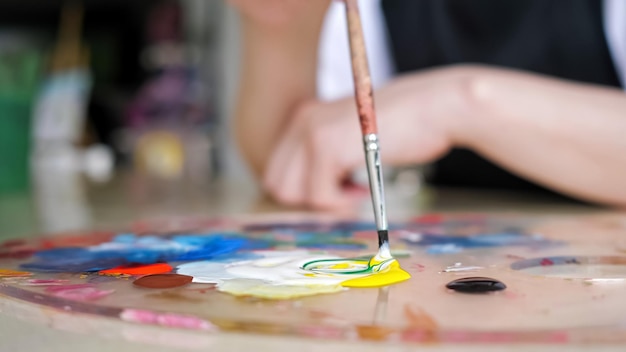 Person mixes bright gouache paint colours with paintbrush