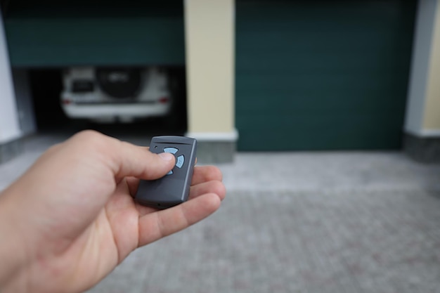 Person opens the garage door in which the car is located with a remote control