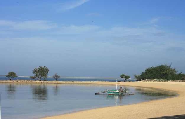 Человек в лодке на море на фоне голубого неба