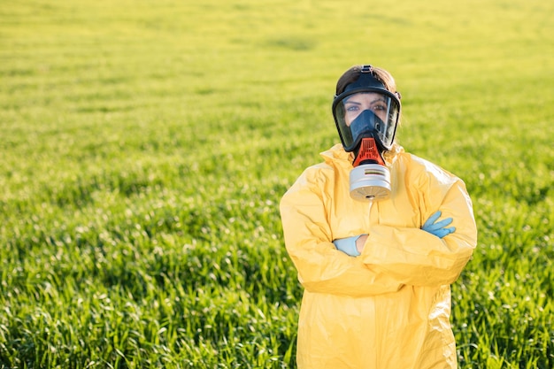 Person in overalls and gas mask call to save the planet while standing on green field on sunset Concept of bad ecology and environmental protection