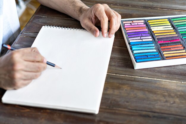 Person painting with a pastel crayon chalk on sketchbook