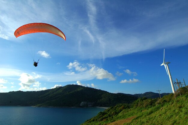 Person paragliding over mountains against sky