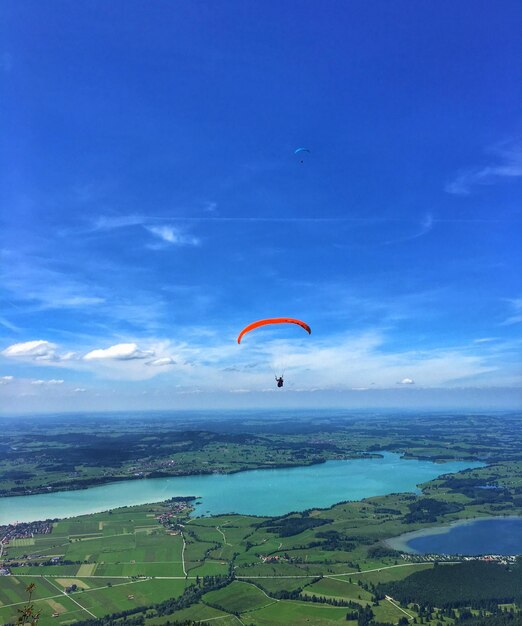 青い空に照らして海の上をパラグライダーで飛ぶ人