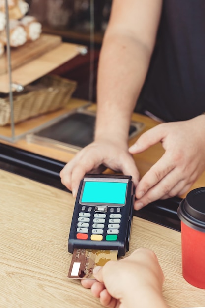 Person pays for takeaway coffee using a smartphone through a payment terminal in an outdoor cafe