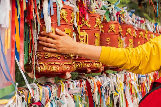 Person pilgrim female hand touching turning spinning buddhist prayer wheel at buddhist monastery