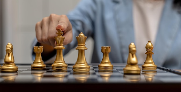 Person playing chess board game, business woman concept image holding chess pieces like business competition and risk management, planning business strategies to defeat business competitors.