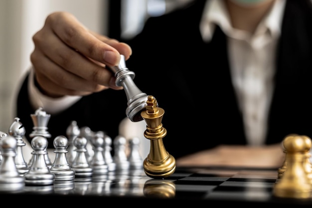 Person playing chess board game, conceptual image of businesswoman holding chess pieces against opponent chess against business competition, planning business strategies to defeat business competitors