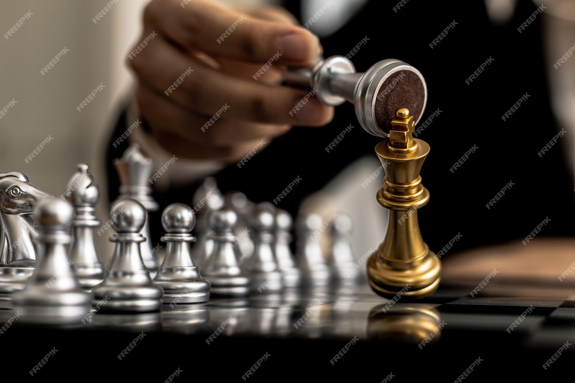 Close up of hands of a business man moving king golden chess to defeat  opponent the chess game is development analysis, strategy, and plan, the  management or leadership concept. 22804709 Stock Photo