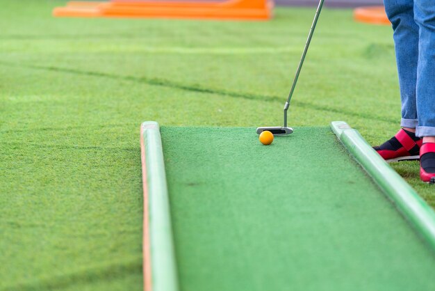 Person playing a game of miniature golf on artificial green turf