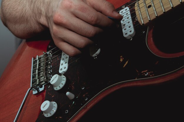 Photo person plucking the strings of an electric guitar with a pick. selective focus. copy space.