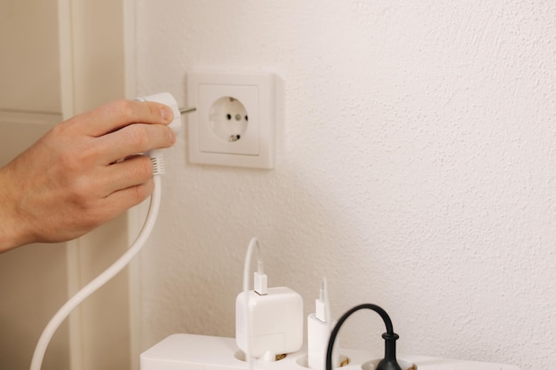 A person plugging a plug in a wall outlet.