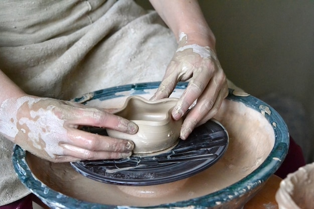 Person potter makes earthen pot on a potter's wheel