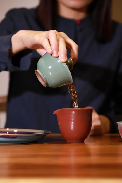 A person pouring a cup of tea from a teapot.