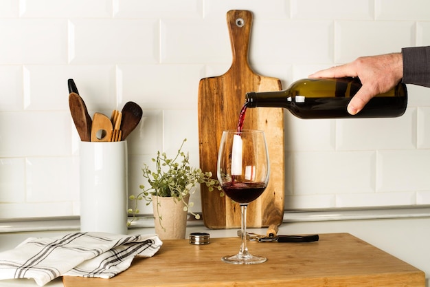 A person pouring a glass of red wine into a wooden table.