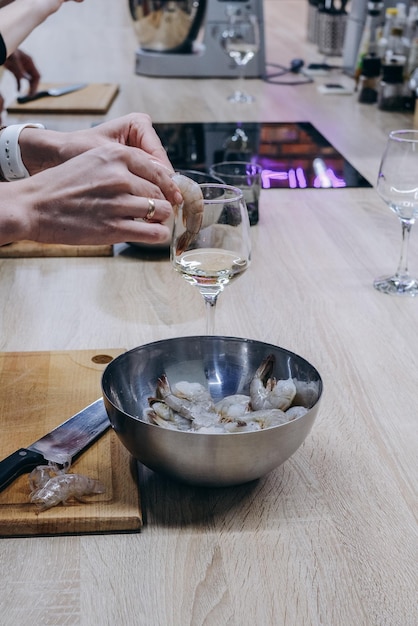 A person pouring a glass of white wine into a bowl.