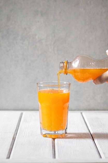 A person pouring orange juice into a glass