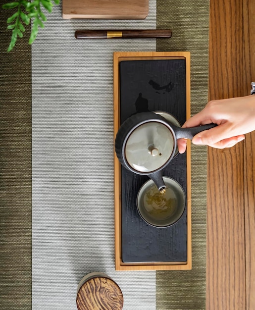 A person pouring tea into a cup on a table Tea for relaxation and rejuvenation