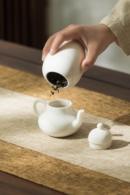 A person pouring tea into a white teapot