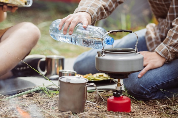 A person pouring water into a kettle for his tea