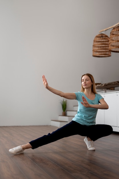 Foto persona che pratica il tai chi al chiuso