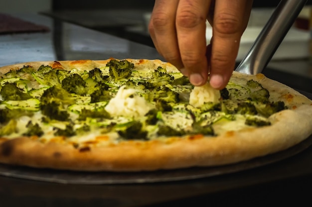 Person preparing a Broccoli Pizza.