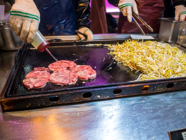 キッチンでバーベキューグリルで食べ物を準備している人