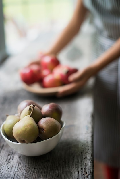 A person preparing organic fresh produce in a kitchen Tray of red apples Bowl of pears