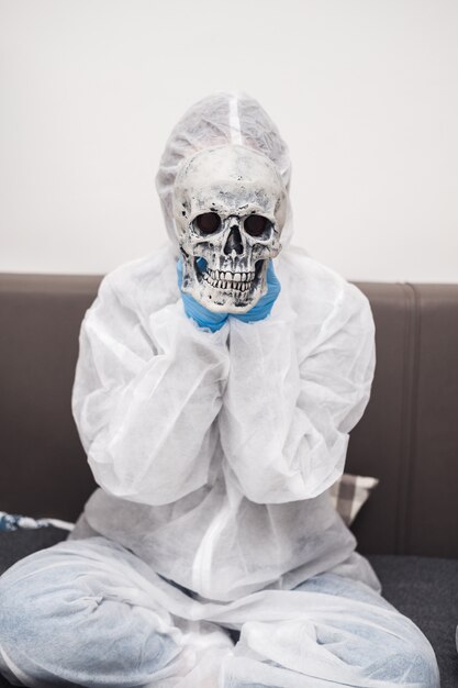 Person in protective suit holds skull in his hands in front of his face