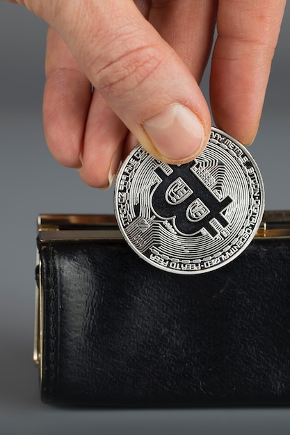 Foto la persona mette bitcoin in un portafoglio nero. avvicinamento